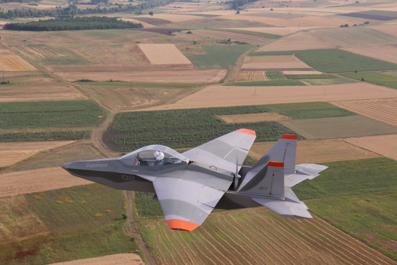 Photo looking down of an SF-1 Archon flying over cultivated fields.